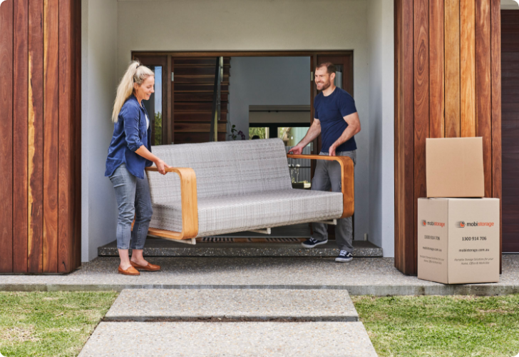 A couple moving a couch outside their home